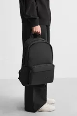 Mochila negra con acabado engomado, compartimento principal con cierre de cremallera, bolsillo interior con cierre, bolsillo frontal con cierre, bolsillos laterales planos, respaldo acolchado con sujeción para equipaje, asa de mano y dos asas de hombro ajustables y acolchadas.