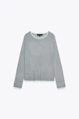 Sweater gris de punto con cuello redondo y mangas largas. Tiene ribetes blancos en cuello, puños y ruedo.