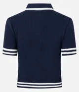 Blusa de punto azul marino con cuello polo blanco, abotonada al frente, de manga corta con rayas blancas en los puños y en el ruedo. Corte ajustado.