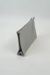 Neceser rectangular de tela sintética color gris claro, con cierre superior dorado.