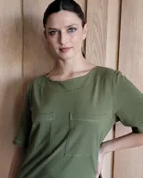 Vestido midi negro con cuello redondo y mangas cortas. Presenta dos bolsillos cuadrados en el pecho y ribetes blancos en cuello, mangas, bolsillos y ruedo.