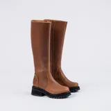 Bota de caña alta color marrón, confeccionada en cuero vacuno. Tiene suela de goma sport artesanal, cierre YKK del lado interno y horma de punta redonda.