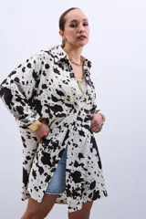 Camisa oversize blanca con estampado de manchas de vaca en color negro, de mangas largas y cuello camisero.