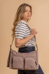 Bandolera de tela impermeable color topo, con dos compartimientos principales y dos bolsillos frontales con cierre. Posee correa regulable con hebilla.