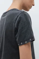 Remera de algodón color bordó, con cuello redondo, manga corta y detalle de ojalillos metálicos en el borde de las mangas.