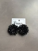 Par de aros negros con forma circular, hechos con pequeñas cuentas facetadas.
