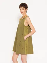 Vestido corto negro de poplín con cuello redondo y sin mangas. Presenta apliques de piedras negras en la parte delantera y trasera.