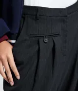 Pantalón de vestir de corte recto, color gris oscuro con finas rayas verticales (raya de tiza). Presenta pliegues frontales y tiro alto.