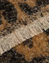 Bufanda tejida de lana en tonos beige y negro, con estampado geométrico y terminación en flecos.