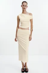 Falda midi color crema, de tiro alto con cintura elástica y detalle de pliegues laterales.
