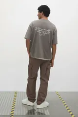 Pantalón cargo color marrón topo, de corte relajado, confeccionado en popelina de algodón. Cuenta con bolsillos al bies, bolsillos traseros con solapa y bolsillos laterales en las piernas con solapa y botones a presión.