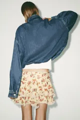 Minifalda color crema con estampado floral en tonos rojos y verdes. Presenta volados con puntilla en el ruedo.