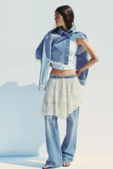 Falda corta de encaje color crema con forro interior. Presenta cintura elástica y bajo asimétrico con terminación en picos.