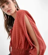 Blusa color ladrillo con escote redondo con ajuste, mangas largas con aberturas en los hombros y elástico en la cintura.