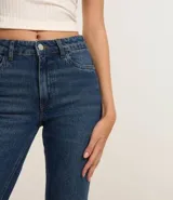 Pantalón de jean azul oscuro, modelo cropped flare, con bolsillos delanteros y traseros, y cintura con trabillas.