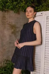 Vestido corto azul con lurex, sin mangas y con volados en el ruedo. Diseño de líneas verticales.