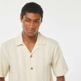 Camisa de manga corta color crema con textura de punto y botones de madera.