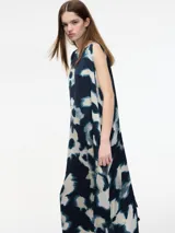 Vestido largo sin mangas con estampado abstracto en tonos negro, marrón, blanco y verde. Tiene cuello redondo, corte amplio y tajos laterales.