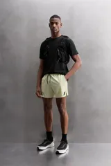 Shorts deportivos color verde oliva confeccionados en tejido técnico ligero y elástico. Cuenta con forro interior, cintura elástica ajustable con cordón, bolsillos laterales, bolsillo de seguridad en espalda con cierre de cremallera, bajo con aberturas laterales y logo estampado en la pierna.