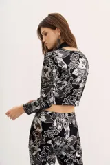 Blazer negro de terciopelo con estampado floral plateado, corte cropped y mangas largas.