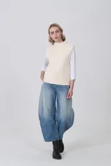 Chaleco de punto color crema, sin mangas, con cuello alto y textura acanalada vertical.