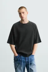 Camiseta negra de corte holgado, cuello redondo y mangas cortas. Tiene un efecto de lavado que le da una apariencia única.