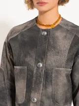 Chaqueta corta de cuero ovino negro con efecto desgastado, cuello mao y cierre frontal con broches metálicos. Presenta bolsillos plaqué en el pecho y corte holgado. Marca JCH.