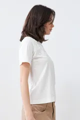 Remera color crudo de algodón, de corte recto y manga corta, con bordados calados en el escote.