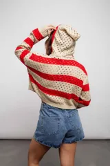 Buzo de punto calado a rayas horizontales en tonos beige y negro, con capucha y corte holgado.