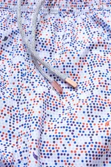 Short de baño blanco con estampado de lunares azules y naranjas. Cuenta con cintura elástica con cordón regulable, bolsillos laterales y bolsillo trasero con cierre.
