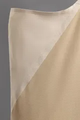 Camiseta deportiva sin mangas color beige, confeccionada en tejido técnico ligero y elástico con estructura perforada. Tiene cuello redondo amplio, sisas con acabados termofijados, bajo con aberturas laterales y logo estampado.