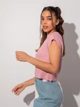 Remera corta de color rosa con textura acanalada, cuello polera y mangas raglán.