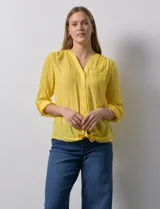 Blusa de gasa color amarillo, marca Zac & Rachel. Cuello a la base, escote en V y abertura central con botones. Delantera con bolsillo aplicado. Largo de manga regulable con presilla y botón. Terminación opcional de nudo en ruedo.