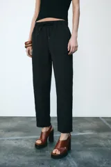 Pantalón tobillero negro con cintura elástica ajustable con cordones, bolsillos delanteros y falsos bolsillos con solapa en la espalda.