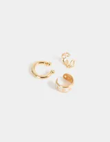 Set de tres aros ear cuff dorados. Uno liso, otro con diseño de corazones blancos y otro con diseño de ondas.