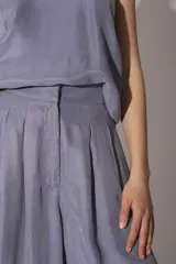 Conjunto de pantalón y top de seda color gris, con cuello halter y corte holgado.