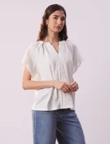 Blusa blanca texturada, marca Sabrina Lauren, con cuello a la base, escote en V con puntilla y lazo, mangas cortas amplias y aplique de puntilla.