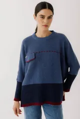 Sweater beige de lana con mangas 3/4, corte holgado, detalle de costuras rojas y bolsillo pequeño en el pecho.