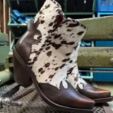 Bota corta de cuero marrón con apliques de cuero vacuno con manchas blancas y marrones. Tiene taco de madera y puntera cuadrada.