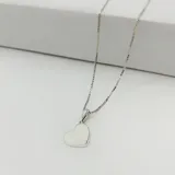 Conjunto de collar con cadena de eslabones tipo caja y dije de corazón liso y pulido. El metal es plateado.