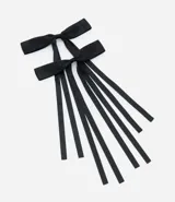 Par de pinzas para el pelo tipo pico de pato, con moña de tela negra y tiras colgantes.