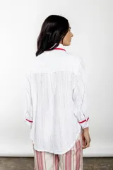 Camisa blanca de broderie con detalles en bies rojo, corte amplio y estilo relajado.