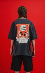 Remera negra de manga corta con cuello redondo y calce oversize. Estampado frontal con Mickey Mouse en un diseño gráfico con detalles en naranja.