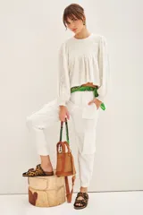 Pantalón blanco de corte holgado, con cierre y botones en el delantero, elástico en la cintura y en el ruedo. Posee bolsillos laterales y en las piernas.