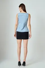 Chaleco de jean celeste con corte ajustado, cuello cuadrado, cierre frontal con botones metálicos y bolsillos de parche en el pecho.