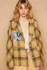 Blazer amarillo con estampado a cuadros en tonos verde y marrón. Tiene bolsillos de solapa, botones metálicos en la parte delantera y en los puños.