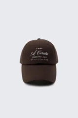 Gorra de béisbol color marrón con bordado blanco en el frente con la inscripción "Zara A Coruña Established 1975 Rua Juan Flórez 64-66".