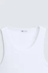 Musculosa blanca de algodón con cuello redondo y sisas amplias, corte ajustado.