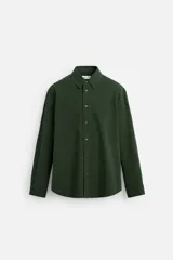 Camisa verde oscuro de algodón con textura jacquard, corte relaxed fit, cuello solapa, manga larga con puños abotonados y cierre frontal con botones.