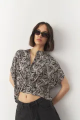 Blusa de manga corta con estampado de hojas en tonos negro y blanco, con cuello mao y botones a tono.